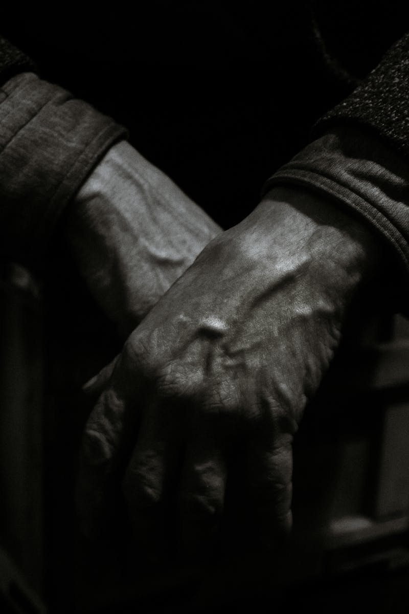 Dramatic black and white close-up photo showcasing aged hands folded together, expressing emotion and texture.